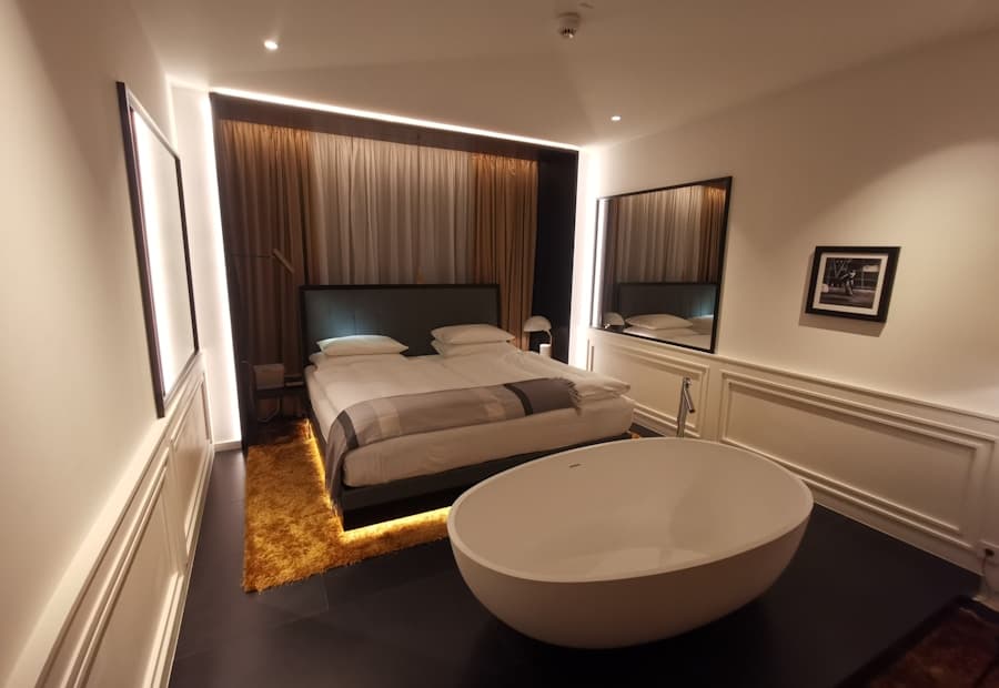 A luxury bedroom with a freestanding bathtub and warm recessed lighting
